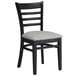 A black Lancaster Table & Seating wood ladder back chair with a light gray vinyl seat.