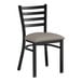 A black metal Lancaster Table & Seating ladder back chair with a dark gray vinyl padded seat.