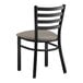 A Lancaster Table & Seating black metal ladder back chair with a dark gray cushion.