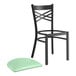 A black Lancaster Table & Seating cross back chair with a seafoam vinyl cushion