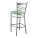 A Lancaster Table & Seating clear coat finish cross back bar stool with a seafoam vinyl padded seat.
