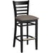 A black Lancaster Table & Seating wood bar stool with a taupe vinyl seat and ladder back.