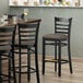 A Lancaster Table & Seating black wood bar stool with a taupe vinyl seat detached.
