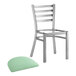 A Lancaster Table & Seating silver metal ladder back chair with a seafoam vinyl padded seat.