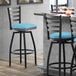 A Lancaster Table & Seating black ladder back swivel bar stool with a blue cushion.