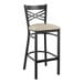 A black Lancaster Table & Seating bar stool with a light gray cushion.