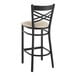 A Lancaster Table & Seating black cross back bar stool with a light gray cushion.