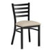 A black Lancaster Table & Seating ladder back chair with light gray vinyl padded seat.