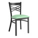 A black Lancaster Table & Seating metal chair with a seafoam green cushion.