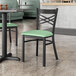 A Lancaster Table & Seating black cross back chair with a seafoam green cushion on a table in a restaurant.