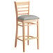 A Lancaster Table & Seating wooden bar stool with a light gray cushioned seat.
