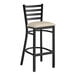 A black Lancaster Table & Seating ladder back bar stool with a light gray vinyl padded seat.