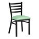 A Lancaster Table & Seating black metal ladder back chair with a seafoam vinyl padded seat.