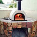 A WPPO Tuscany wood-fired pizza oven with a fire inside.