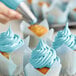 Rich's Allen Pastel Blue Buttrcreme Icing being piped onto a cupcake with a blue frosting tip.