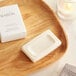 A white Babor body soap bar on a wooden tray next to a candle.