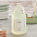 A white jug of Babor Energizing Lime & Green Tea shampoo sitting on a counter next to towels.