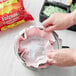 A person's hands holding a pink coffee filter pack.