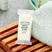A small white package of Serene Elements body bar soap on a wooden surface next to a towel.