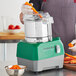 A person using the AvaMix Revolution combination food processor to chop a carrot.