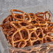 A Tom Sturgis Thin Pretzels container on a table filled with pretzels.