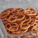 A clear container filled with Tom Sturgis pretzels on a counter.