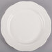 A CAC ivory china plate with a scalloped edge on a gray surface.