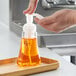 A hand pouring Dial Citrus Sunburst foaming hand soap into a soap dispenser on a kitchen counter.