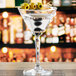 A close up of a martini glass with olives on top.