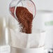 A measuring cup full of Toddy Blend Cold Brew Coarse Ground Coffee being poured into a paper bag.