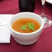 A Tuxton Alaska bright white china bouillon cup filled with soup on a table.