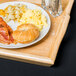 A natural hardwood room service tray with a plate of breakfast food on it.