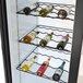 A white Beverage-Air wine rack holding wine bottles in a refrigerator with a glass door.