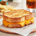 A grilled cheese sandwich made with Daiya Vegan Sliced Cheddar Cheese on a wooden board.