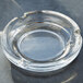 A clear glass Libbey round ashtray on a grey surface.