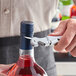 A person using an Acopa Waiter's Corkscrew to open a bottle of red wine.