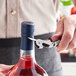 A person using an Acopa Waiter's Corkscrew to open a bottle of wine.