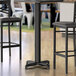 A close-up of a Lancaster Table & Seating black steel bar height table base column.