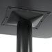 A Lancaster Table & Seating black metal table base with a black pole and square object on top.