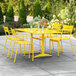 A yellow table and chairs on an outdoor patio.