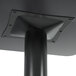 A close-up of a black square table base pole with a square object on it.