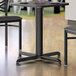 A Lancaster Table & Seating black metal table base with FLAT Tech Equalizer on a wooden surface.