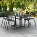 A black Lancaster Table & Seating outdoor table with four chairs on a patio.