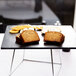 An American Metalcraft black faux slate melamine tray with slices of bread and crackers on a table.
