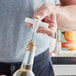 A person using a white plastic pocket corkscrew to open a bottle of wine with a cork.
