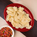 A red Carlisle oval melamine platter with chips and salsa on it.