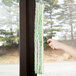 A hand using a Unger Ninja T-Bar to clean a window.
