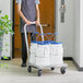 A man using an aluminum dolly to transport four white Choice ice totes with blue lids.