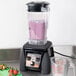 A Waring X-Prep high-power blender with strawberries in it on a counter.