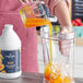A person pouring Capora Peach Fruit Smoothie Mix into a blender.